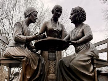three women in bronze sitting at a table